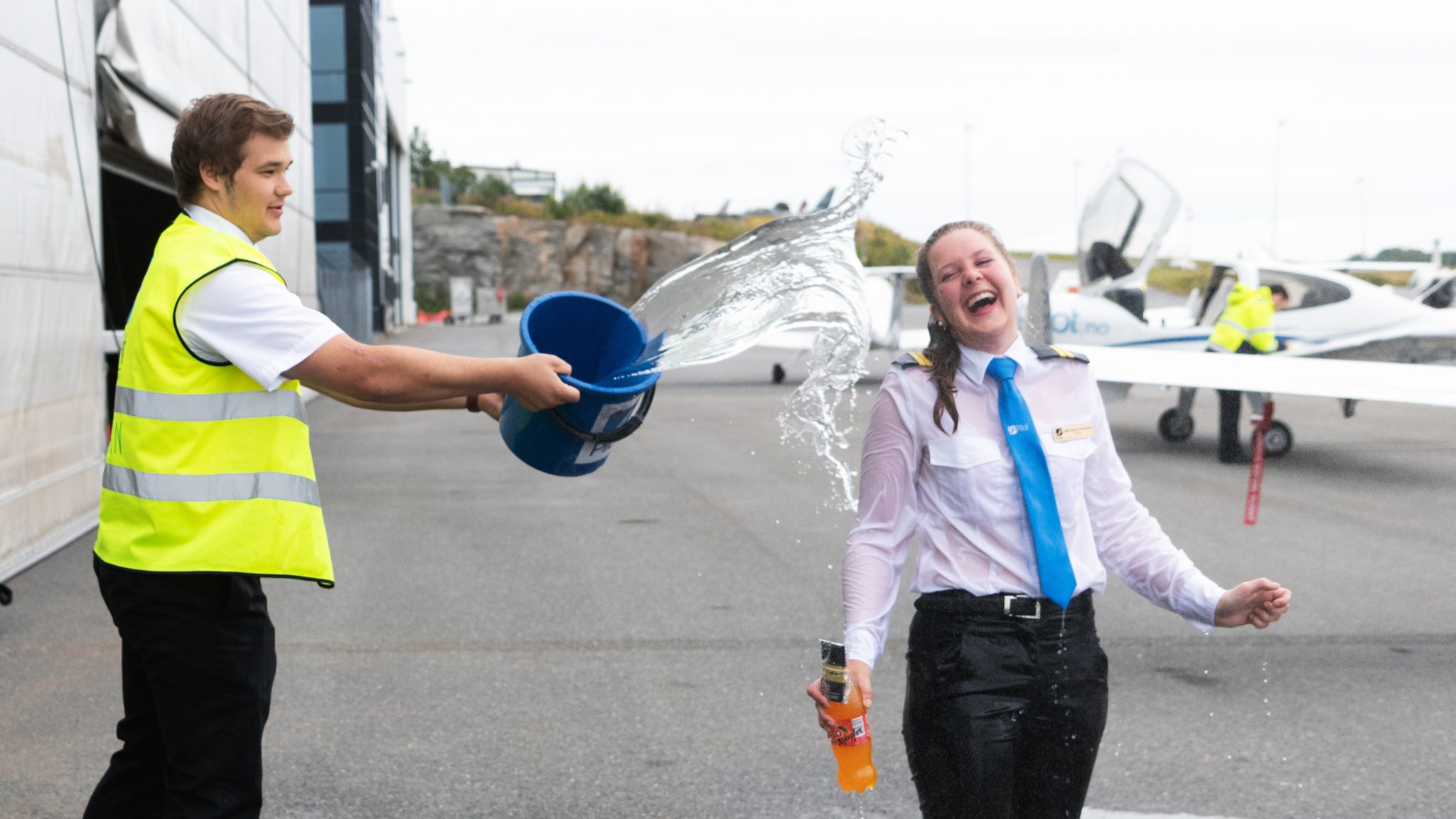Student Taasaasen is being baptized by her fellow student with buckets of cold water after her very first solo flight